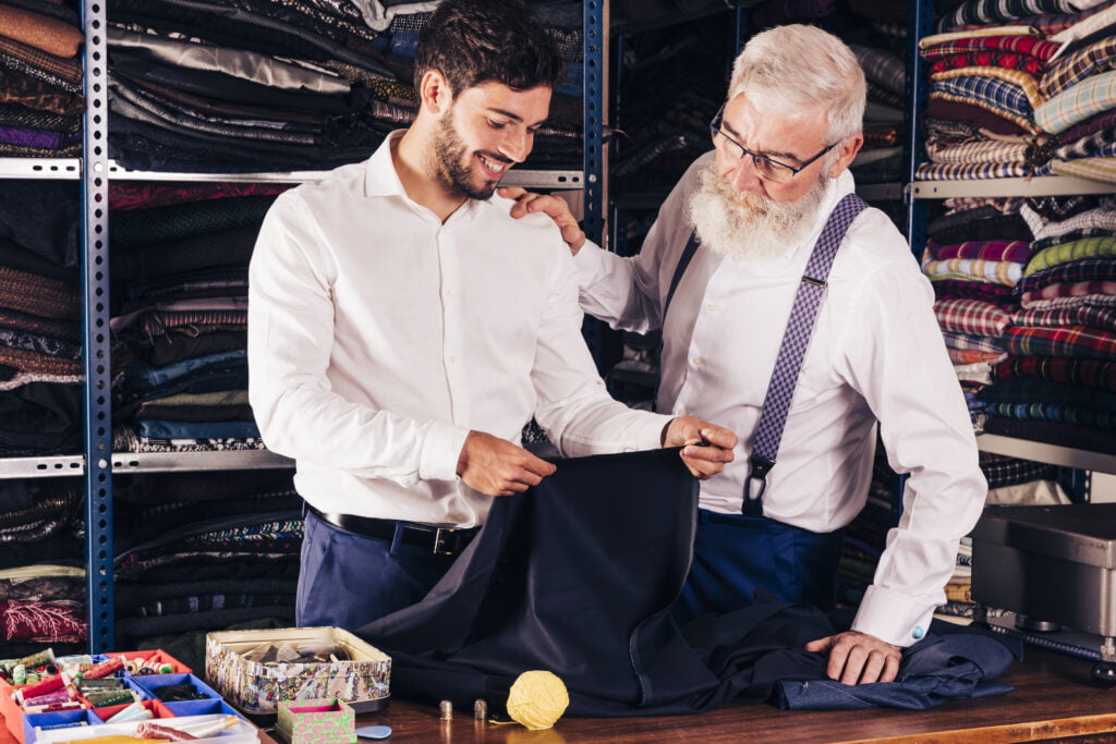 Ritratto di un bel modello di uomo d'affari lumbersessuale hipster che indossa un abito nero casual. Uomo alla moda alla moda in posa seduto sulla sedia in interni di lusso. Pensiero